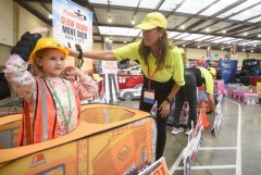 Staff photo by Matt Hamilton / Cindy Iodice, right, helps Evelyn Ingram, 6, as she puts on a toy construction helmet during the Tennessee Tow Show on Oct. 16, 2026, at the Chattanooga Convention Center.