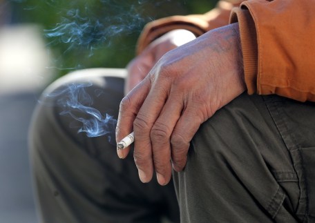 Staff file photo / A man holds a cigarette as he smokes outside the Courts Building in 2019. A recent study found that Chattanooga residents suffering from asthma are more likely to require hospitalization or suffer an asthma-related death than in other major metropolitan areas nationwide.