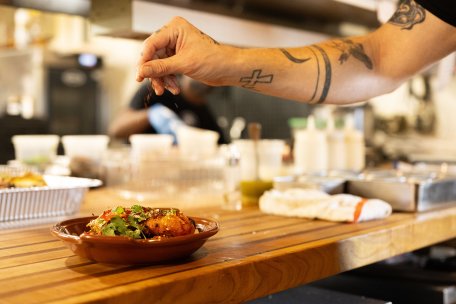 Staff Photo by Seth Carpenter / Chef de Cuisine Cody Baschnegal garnishes a bowl of smoked chicken at Little Coyote on Saturday, Sept. 12, 2026. Little Coyote received the Bib Gourmand award from the Michelin Guide's American South edition for the second year in a row.