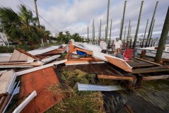 People retrieve belongings from a collapsed boat house in the aftermath of Hurricane Isaias in Destin, Fla., Saturday, Oct. 10, 2026. (AP Photo/Gerald Herbert)